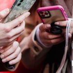 Customer Relationships - Unrecognizable ladies messaging smartphones on street