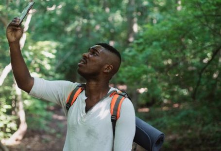 Fear Of Failure - African American male with backpack standing in forest and holding mobile phone while catching GPS signal during hike